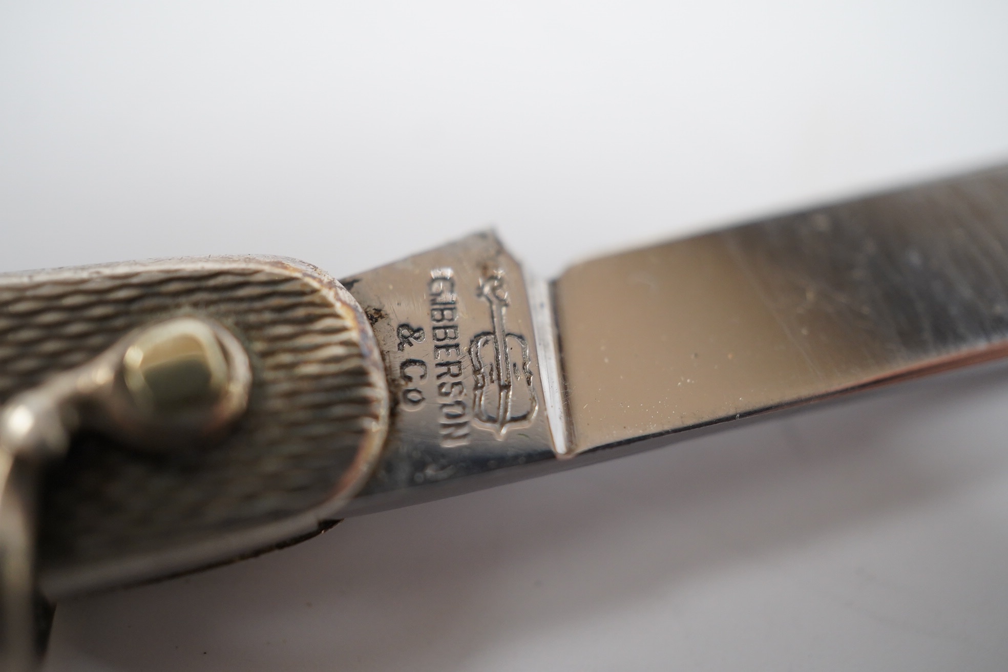 A George V engine turned silver and enamel pocket knife, decorated with R.M.S Queen Mary, the blades lifted by the handles, George Ibberson & Co, Sheffield, 1936, 76mm. Condition - poor to fair